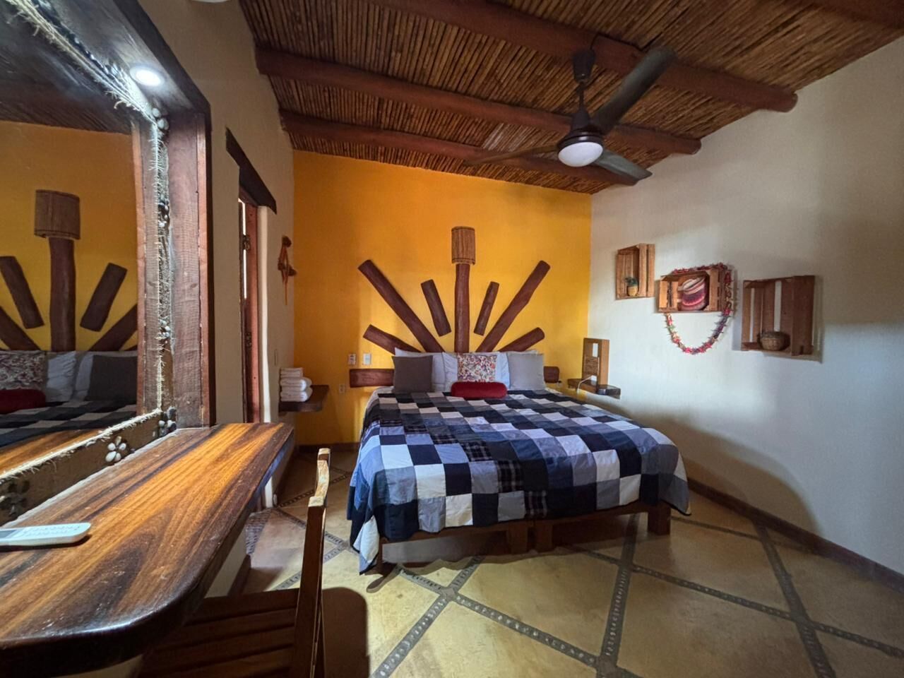 Una habitación con cama, muebles de madera, un espejo y un ventilador de techo.
