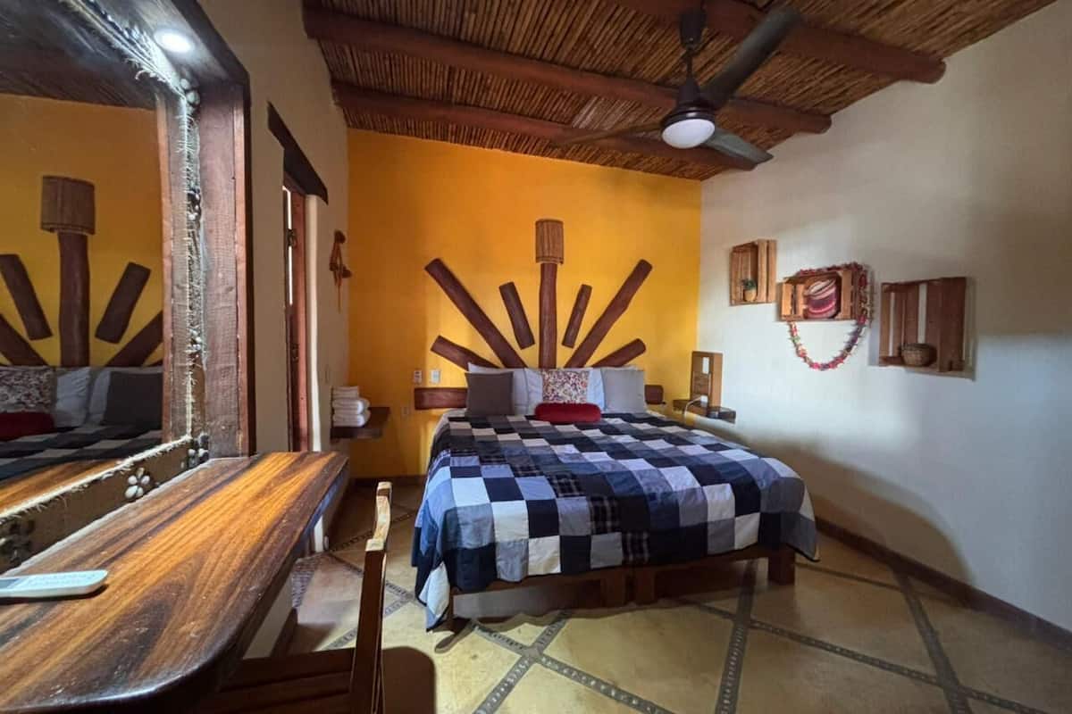A room with a bed, wooden furniture, a mirror, and a ceiling fan.