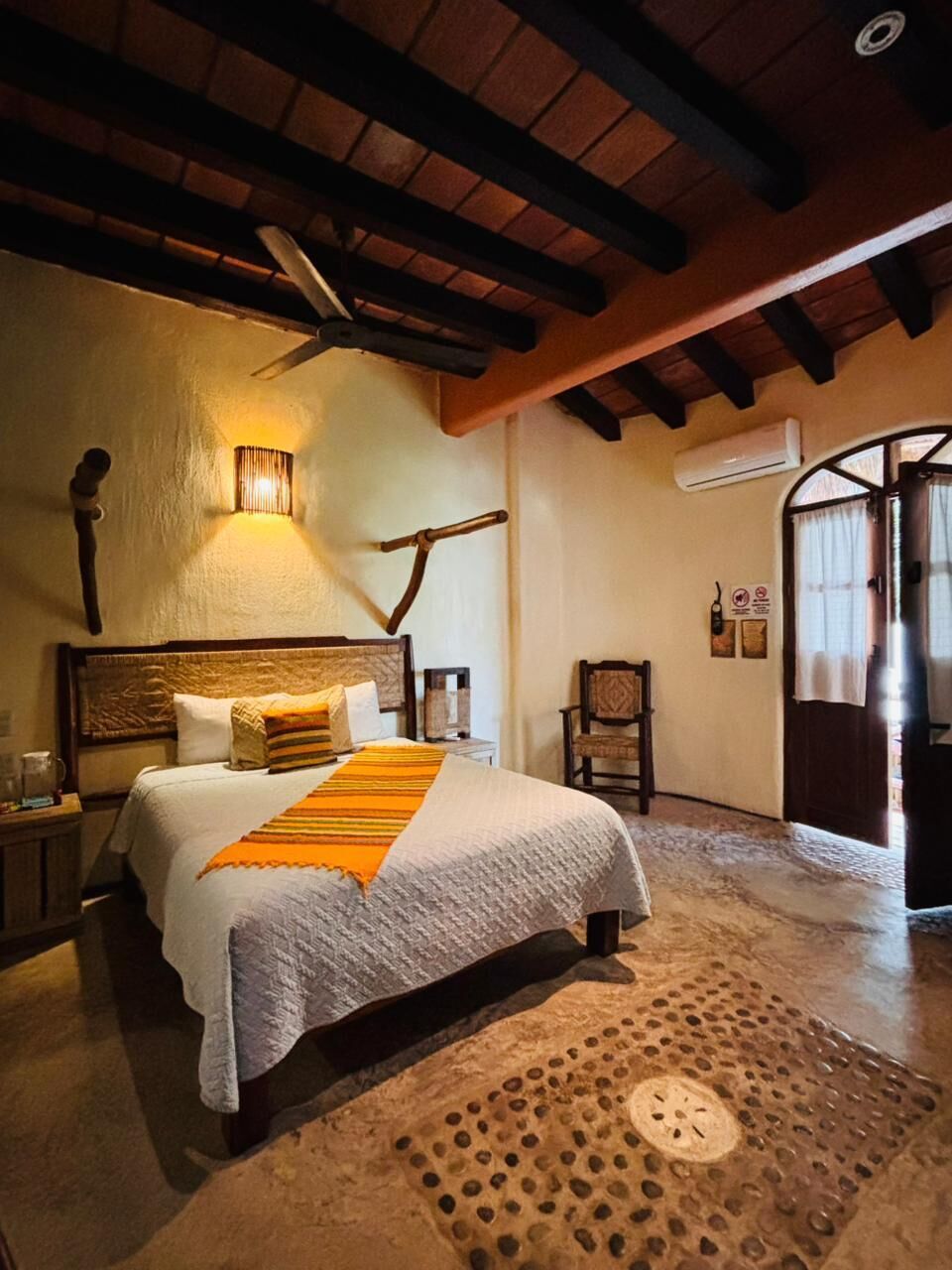 Un dormitorio con cama, una lámpara de pared, una silla y techo de madera.