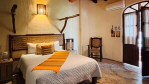A bedroom with a bed, a wall-mounted lamp, a chair, and a wooden ceiling. - Hotel Artesanal  (San Francisco)