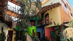 A pool area with a stone pathway, a wooden structure, and a colorful building with a staircase. - Hotel Artesanal  (San Francisco)