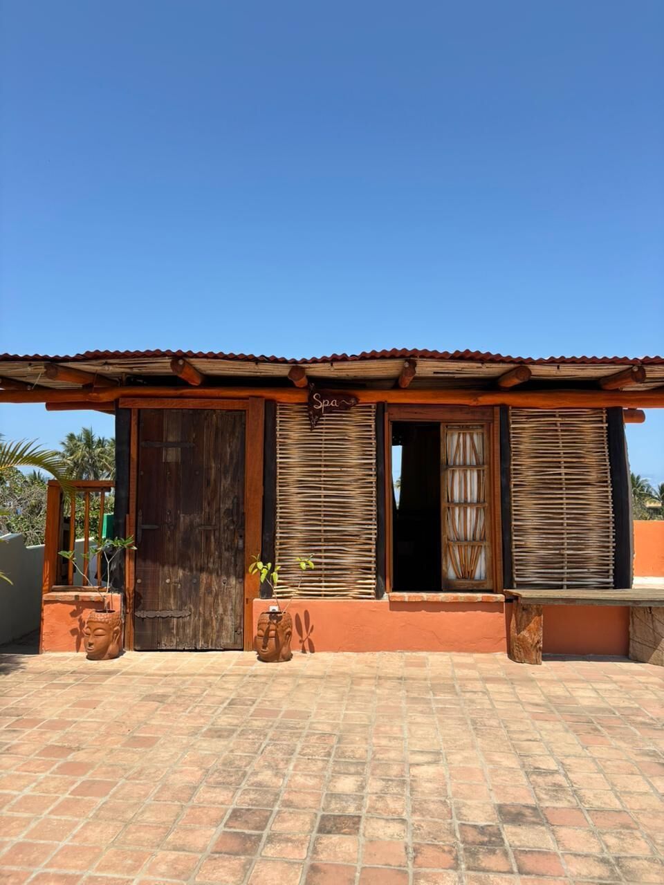 A building with a tiled roof, a wooden door, and a window with curtains.