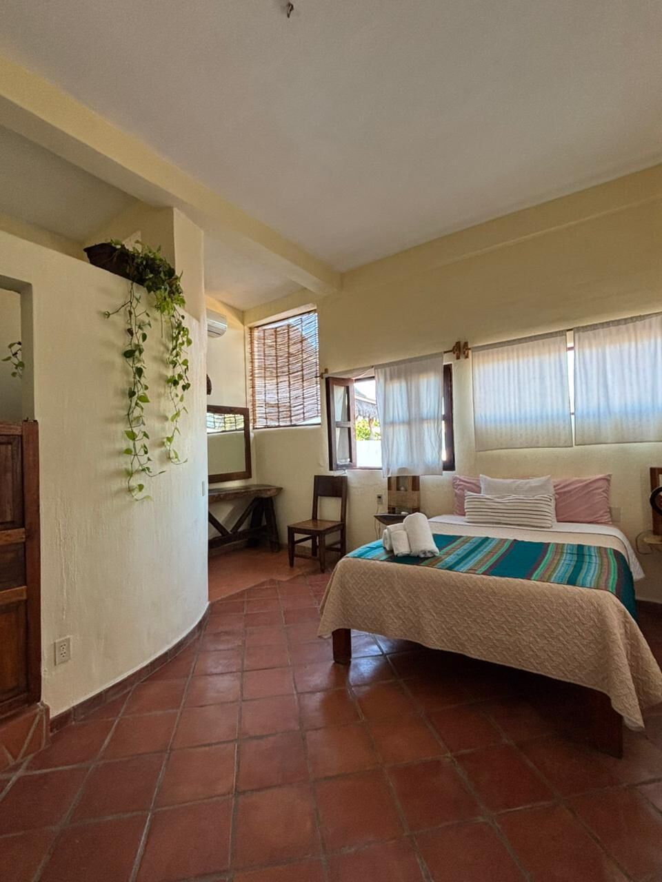 Un dormitorio con cama, escritorio, silla y ventana con persianas.