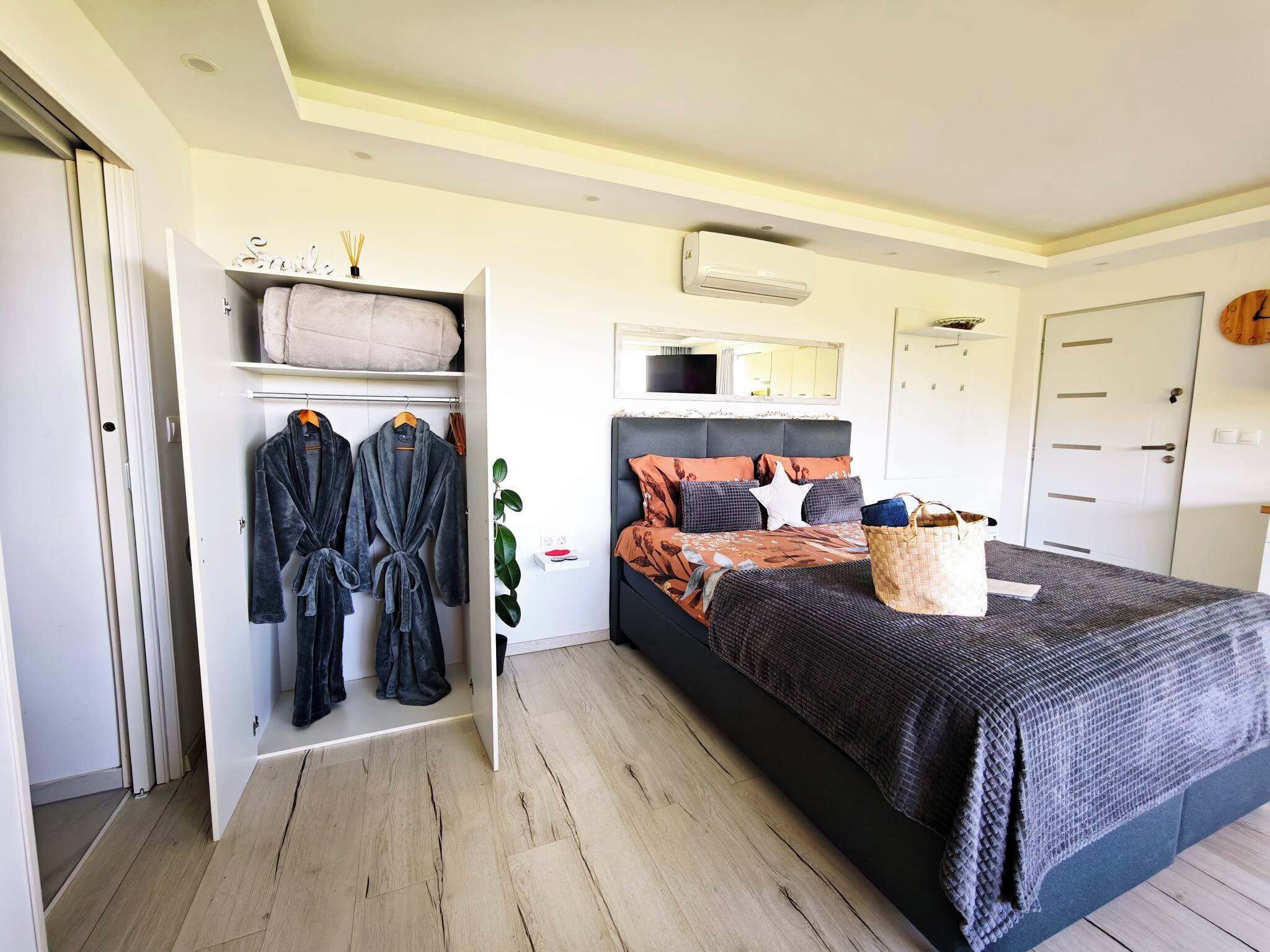Une chambre à coucher comprenant un lit, une armoire, un miroir et un climatiseur fixé au mur.