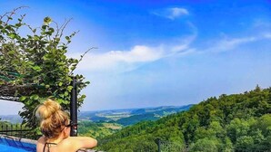 Une personne se détend dans une piscine, avec une vue panoramique sur un paysage boisé.
