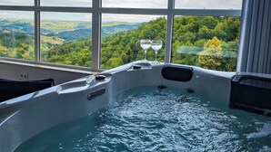 Un bain à remous avec vue sur un paysage montagneux, grâce à de grandes fenêtres.