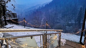 Un espace extérieur enneigé, délimité par une clôture en bois et illuminé par des guirlandes lumineuses.
