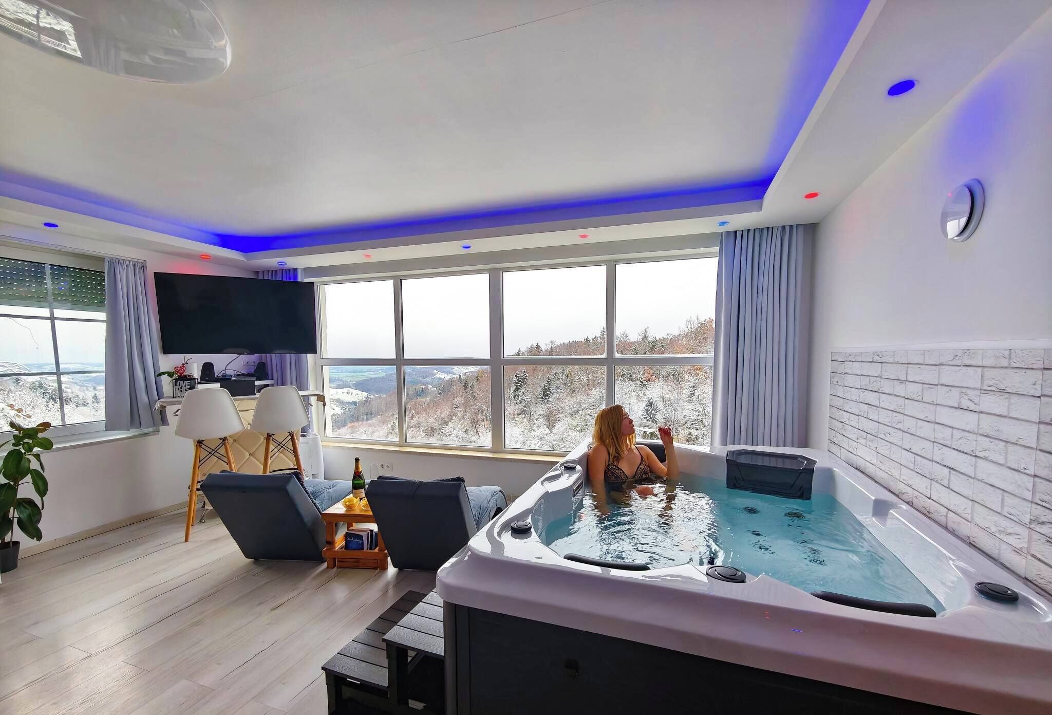 Ein modernes Zimmer mit großem Fenster, einer Whirlwanne und einem Flachbildfernseher.