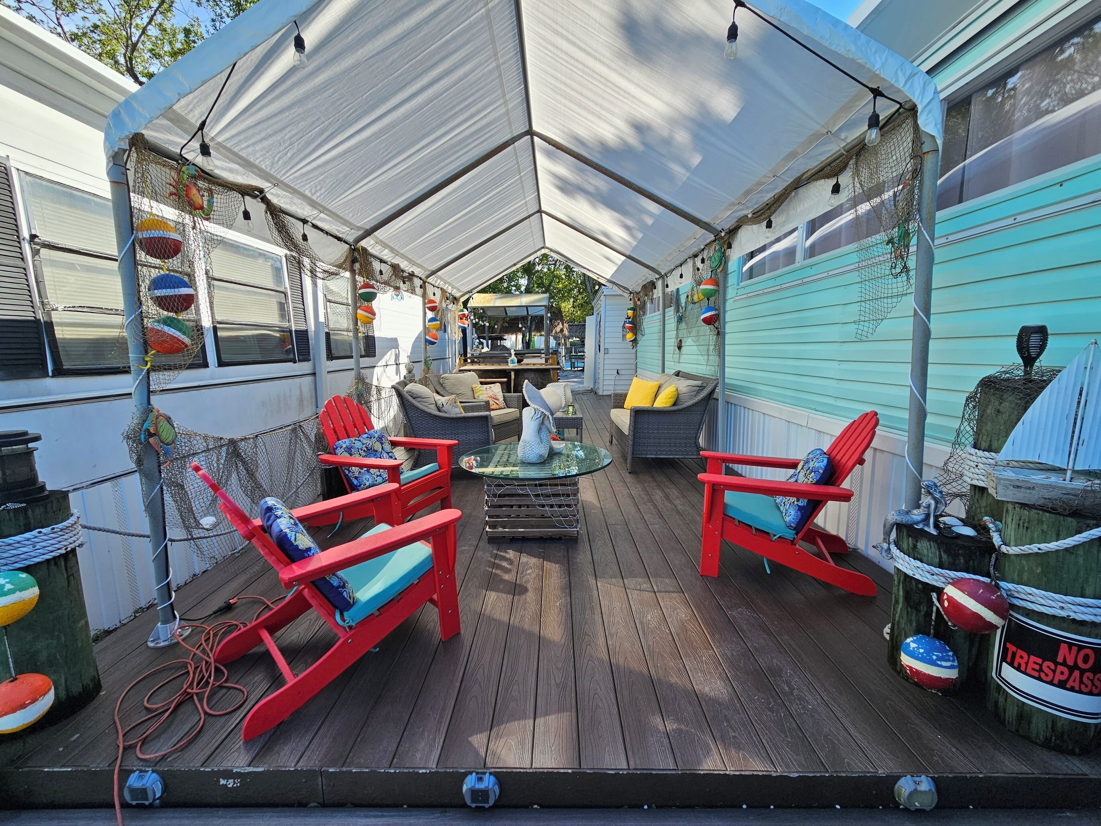 A covered outdoor deck with red chairs and a table, surrounded by a white canopy.