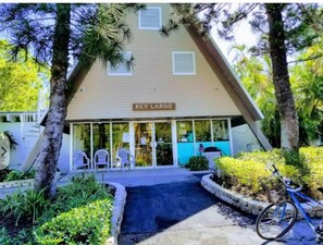 Un bâtiment à Key Largo, avec une enseigne, une entrée abritée et un vélo garé à l’extérieur.