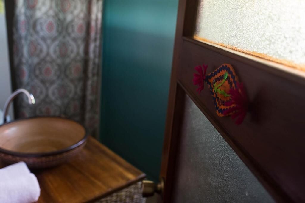 A bathroom with a wooden sink, a towel, and a decorative item on the door.