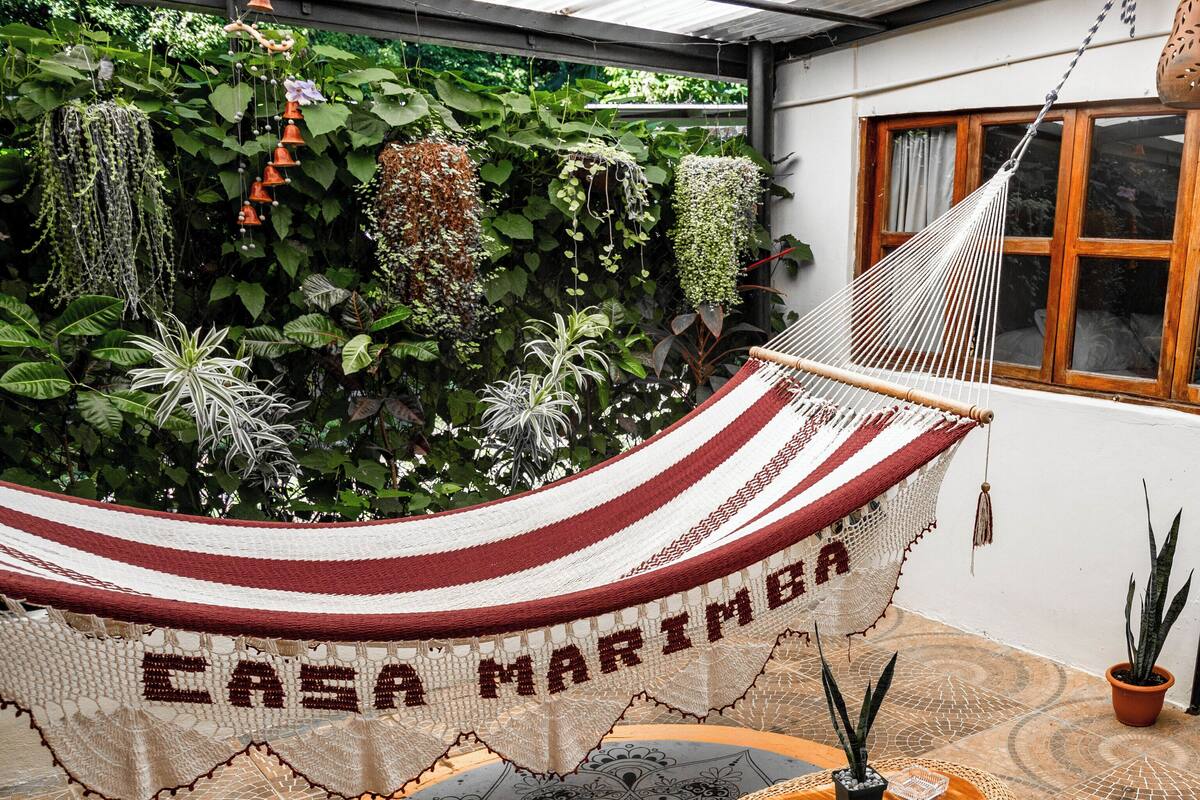 A hammock with "CASA MARIMBA" text, wicker furniture, and a patterned floor.