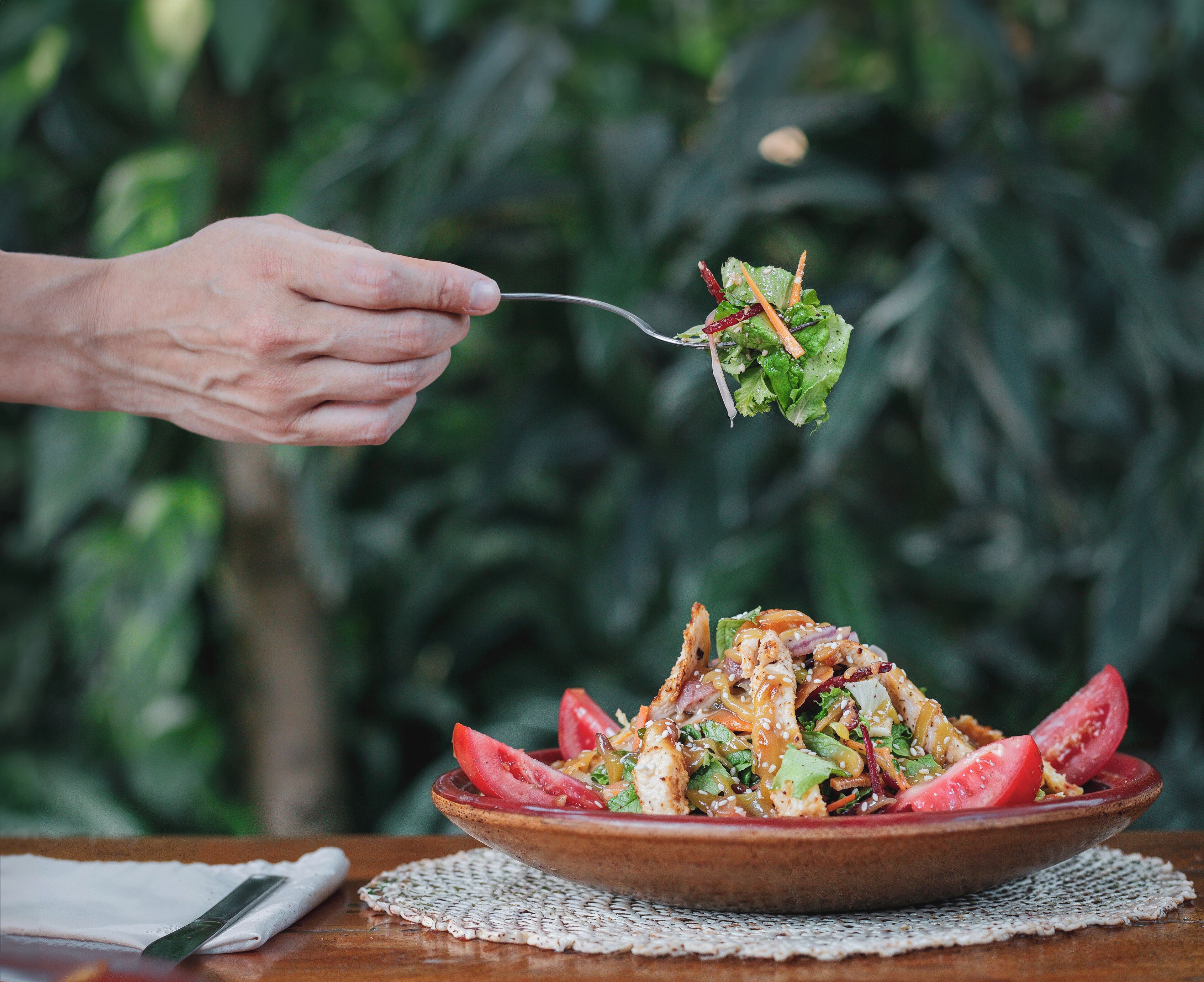 Una mano che tiene una forchetta con un'insalata.