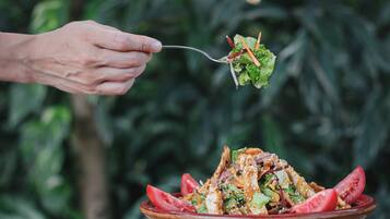 Una mano che tiene una forchetta con un'insalata.