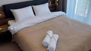 Un lit bien fait, avec des draps blancs et deux serviettes enroulées posées sur le lit.