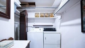 A compact laundry room with a washing machine, dryer, and a small table. - The Eden, 1BR Queen Duplex by Velvet Ditch Villas (Oxford)