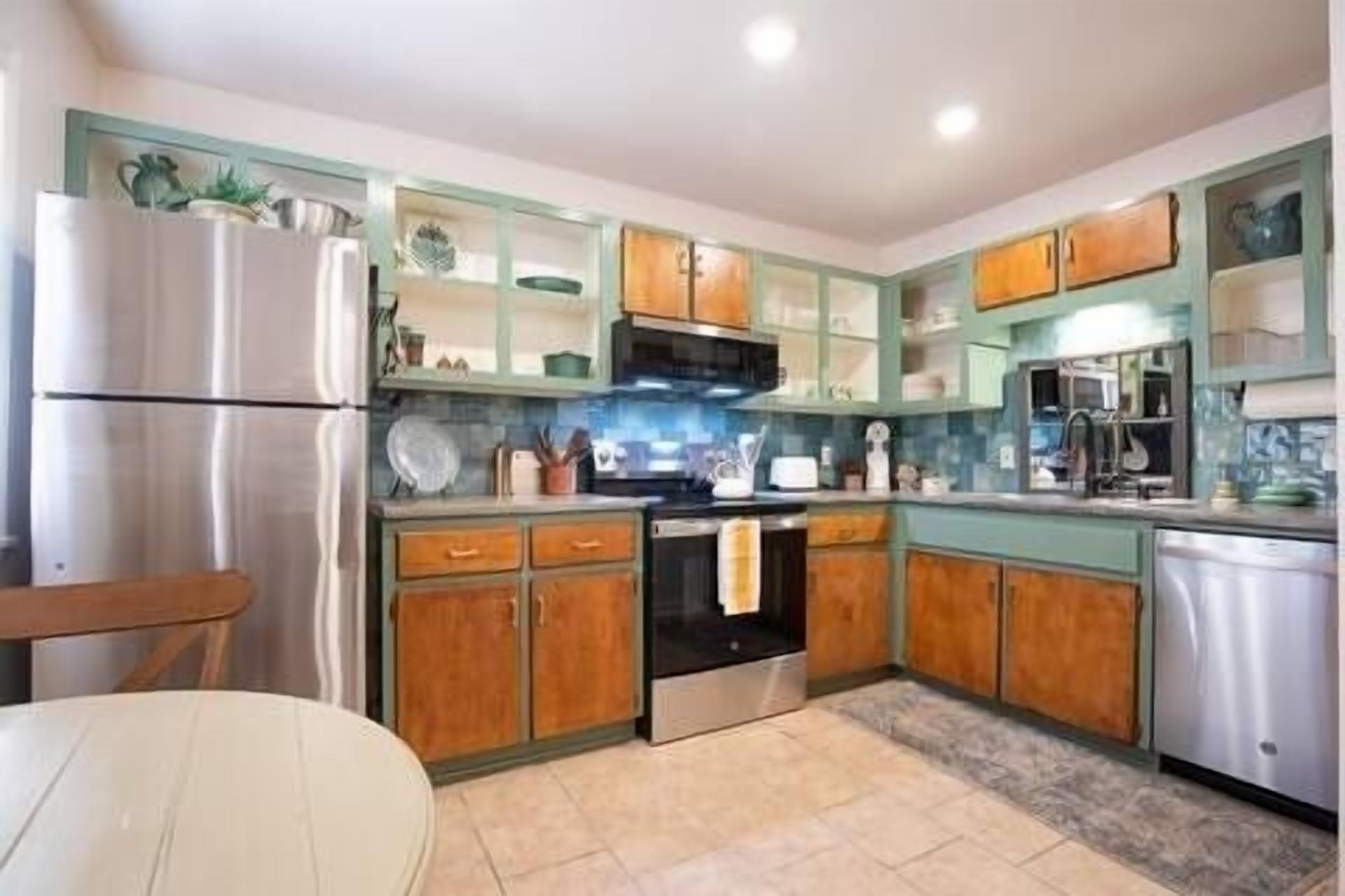 A kitchen with wooden cabinets, a stainless steel refrigerator, and a microwave.