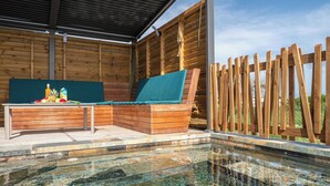 A wooden deck with a bench and table, a clear pool, and a wooden fence.