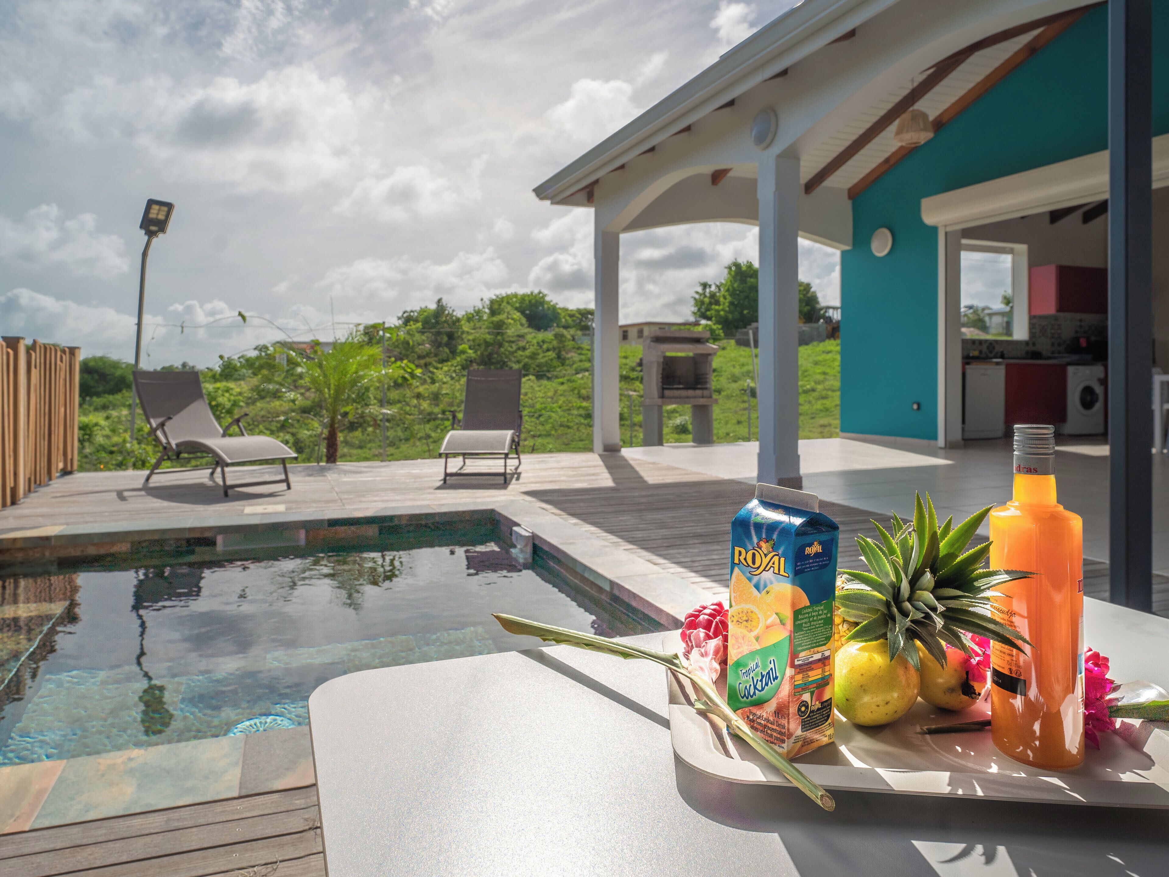 Un espace aménagé au bord de la piscine, avec des chaises longues, des cocktails tropicaux et des fruits frais.