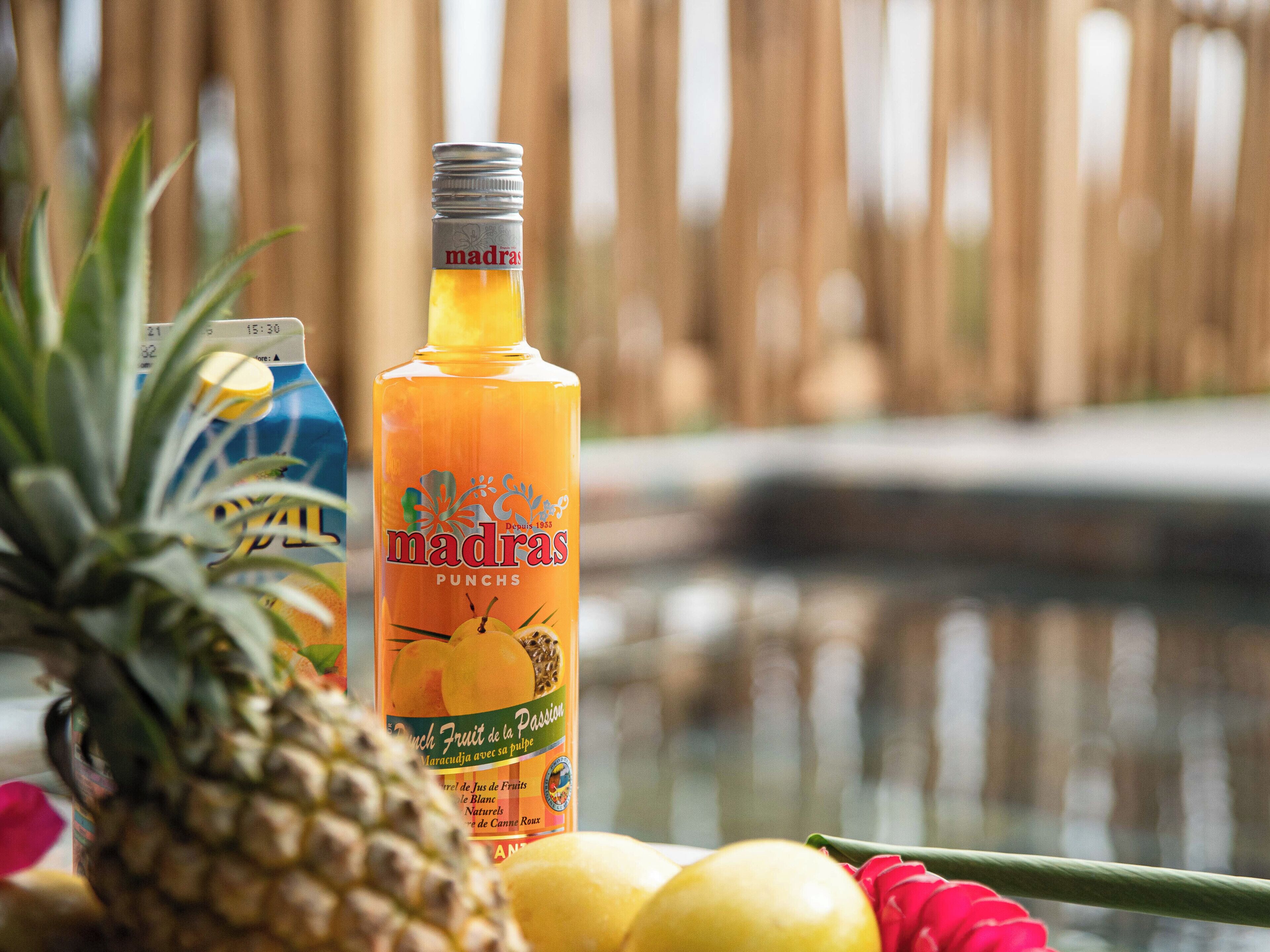 Een fles Madras Punch met een ananas en citroenen op de voorgrond.