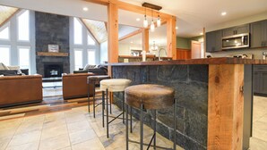 A modern kitchen with a stone island, bar stools, and a fireplace.