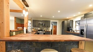 A kitchen with a central island, stone wall, and wooden stools.