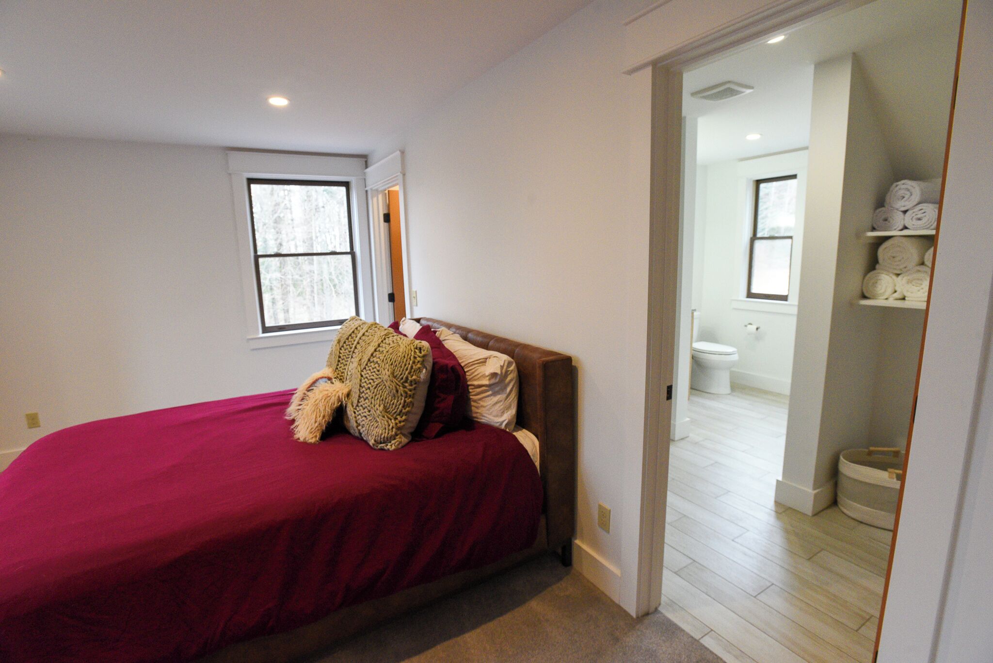 A bedroom with a bed, a window, and a view into the bathroom.