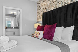 Une chambre d’hôtel avec un lit, un miroir, une salle de bain et un mur décoré de motifs floraux.