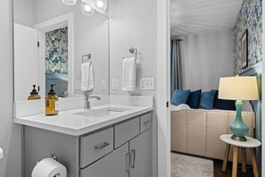 A modern bathroom with a large mirror, two sinks, a toilet, and a vanity with drawers.