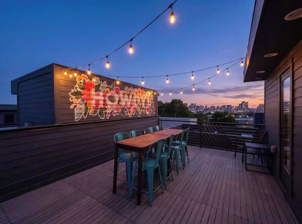 An outdoor dining area with string lights and a neon sign on a building.