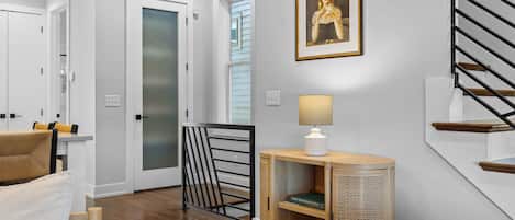 A modern interior with a staircase, a framed portrait, a lamp, and a bookshelf.