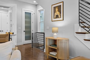 Un intérieur moderne avec un escalier, un portrait encadré, une lampe et une bibliothèque.