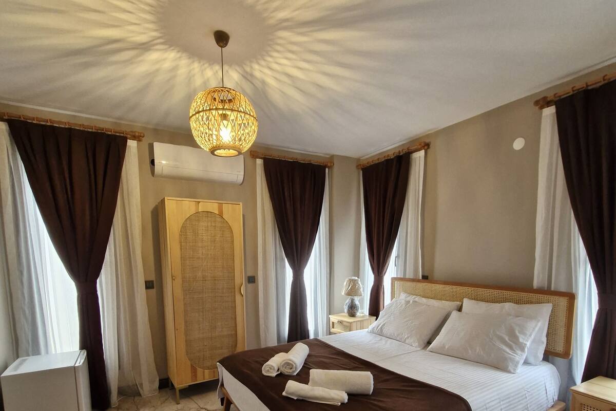 A hotel room with a large bed, a wooden headboard, a nightstand, a lamp, and a ceiling light fixture.