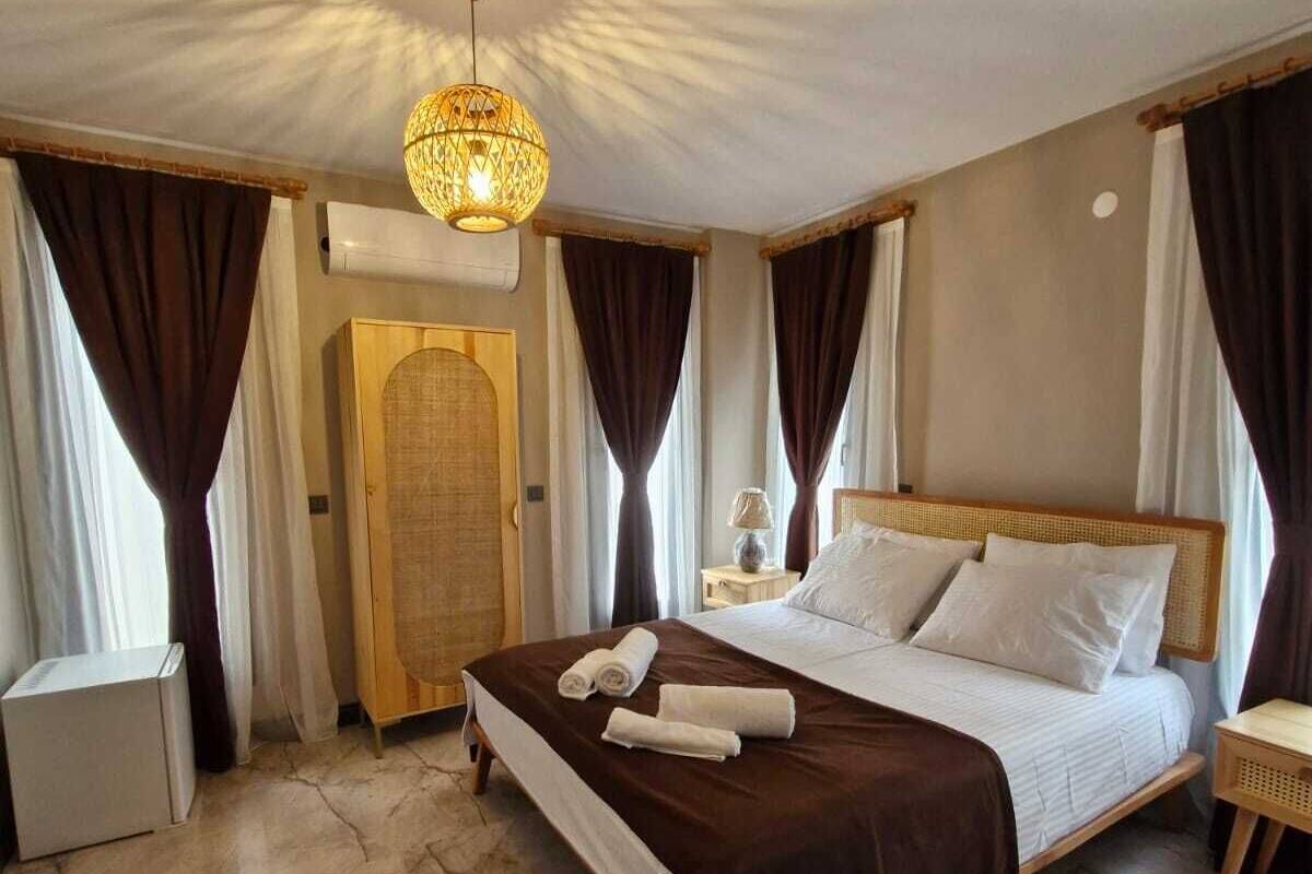 A hotel room with a large bed, a bedside table, a lamp, and a ceiling light fixture.