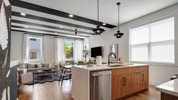 A modern kitchen with wooden cabinets, a dishwasher, and a large window. - 2 Stunning Homes in Nashville | Downtown Views! (Nashville)