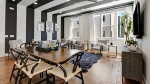 A modern living room with a dining area, large windows, and a ceiling fan. - 2 Stunning Homes in Nashville | Downtown Views! (Nashville)