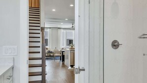 A modern bathroom with a glass shower enclosure and a wooden staircase leading to a living area. - 2 Stunning Homes in Nashville | Downtown Views! (Nashville)
