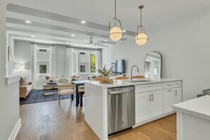 A modern kitchen with a central island, white cabinetry, and pendant lighting.