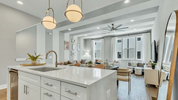 A modern kitchen with a large island, white cabinetry, and pendant lighting.