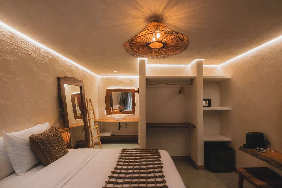 Un dormitorio con cama, lámpara colgante, armario y escritorio con silla.