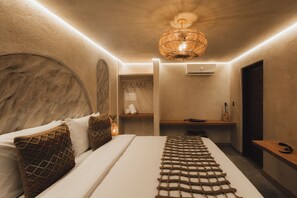 A modern bedroom with a bed, a wooden headboard, a woven light fixture, a bedside table, and a wall-mounted air conditioner. - Pousada Topázio by Amana (Fernando de Noronha)