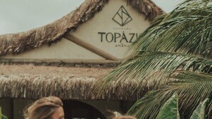 Un edificio con techo de paja y un cartel que dice "TOPAZ".