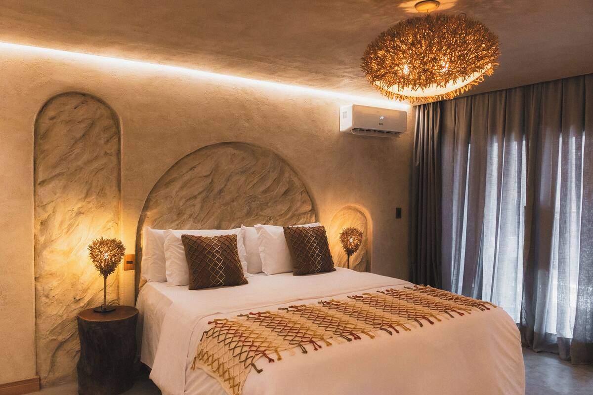 Un dormitorio con una cama grande, un diseño de techo único y una lámpara de araña moderna.