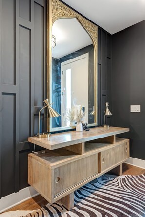 Une salle de bain dotée d’un grand miroir, d’un meuble-lavabo en bois et de deux lampadaires.