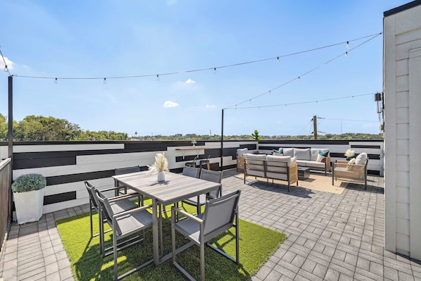 Un patio exterior con una mesa de comedor y sillas, un sofá y una pequeña mesa con un florero.