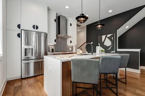 A modern kitchen with a central island, stainless steel appliances, and a black and white backsplash.