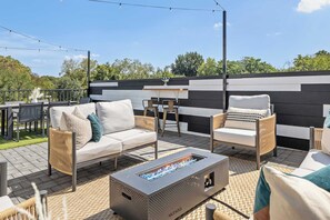 An outdoor patio with a fire pit, seating area, and a black and white wall.