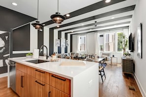 Una cocina moderna con una isla central, armarios de madera e iluminación colgante.