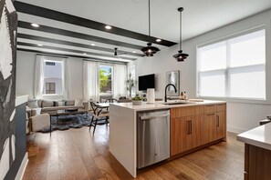 Une cuisine moderne avec des meubles en bois, un lave-vaisselle et une grande fenêtre.