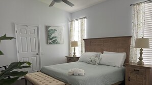 A bedroom with a bed, bedside tables, a bench, a ceiling fan, and a window with curtains. - Near Disney 4Bd/3Ba Villa w/ Private Pool, Hot Tub in Gated Resort Community (Kissimmee)